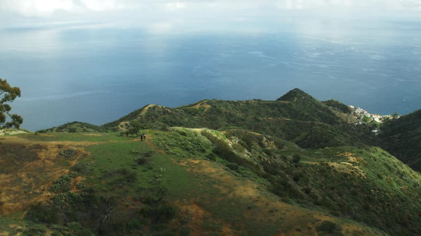 Ship travels in the ocean next to the hilly land