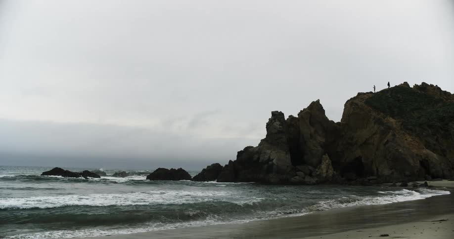 Small waves crashing on the shoreline on the coast on a foggy day
