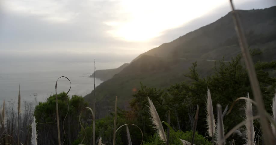 Pale sunlight shines on the verdant mountains on the coast of a landmass