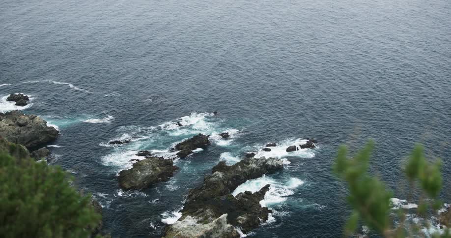 Waves crash onto rocks below a cliff