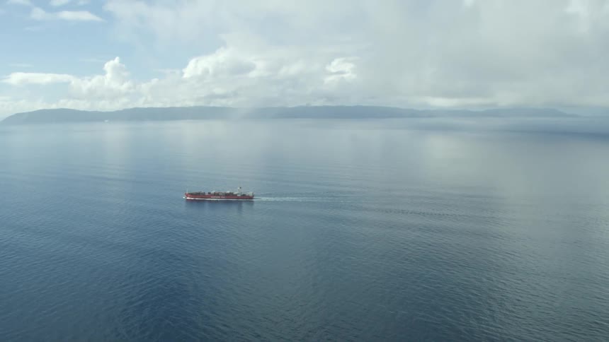 Ship cuts through water while mist covers distant shore