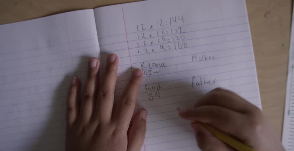 A child writes math problems in a notebook