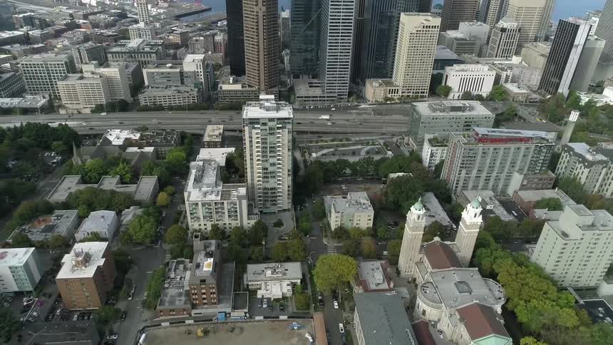 Traffic flows along street past skyscrapers bordering water