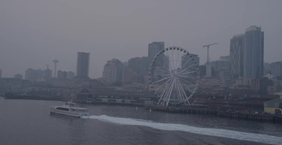 Ferris wheel sits next to the river as a boat travels down the river