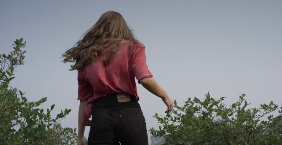 Brunette woman with black shorts and converse shoes walks happily in a cherry orchard