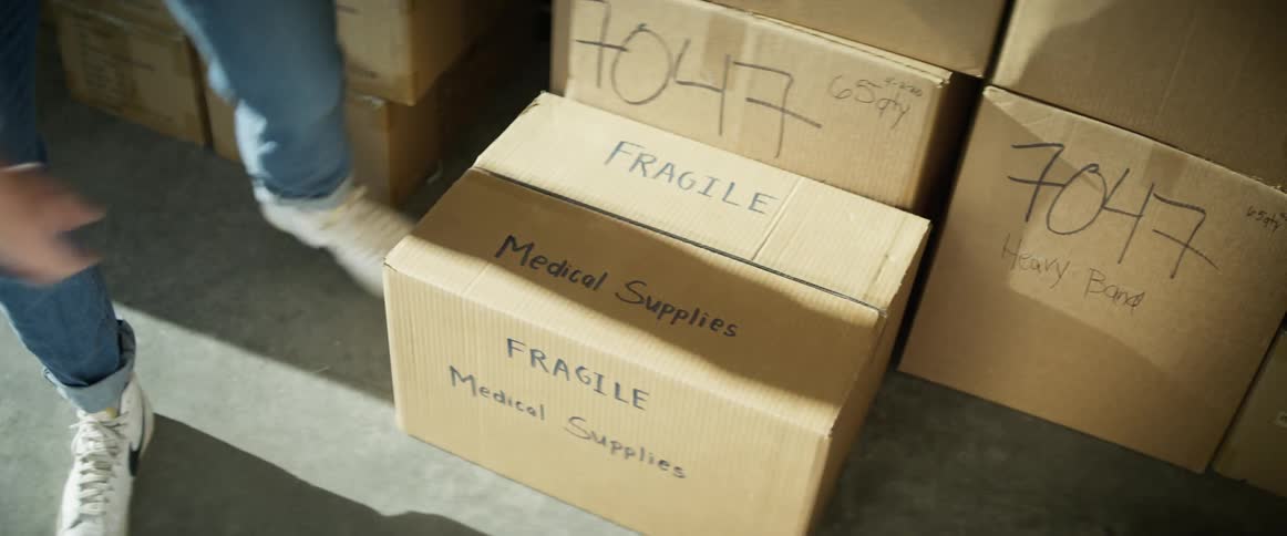 A man carries a box in a warehouse and sets it down