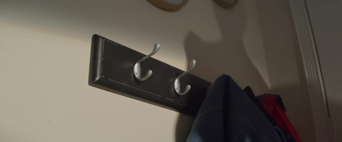 Person grabs a face mask from a coat rack in the wall of the living room