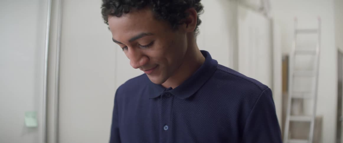 A young man looks down at something he is doing