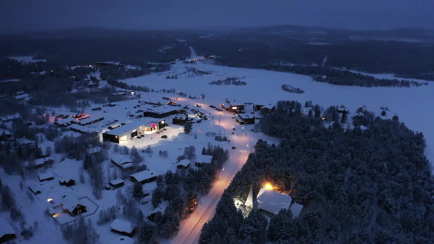 Aerial view of buildings and cars driving in a snowy rural area