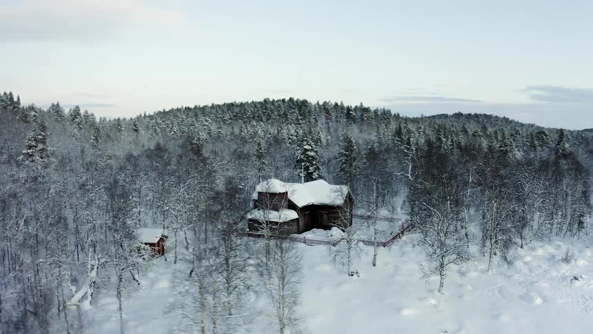 House in the snow covered forest next to the hills at winter