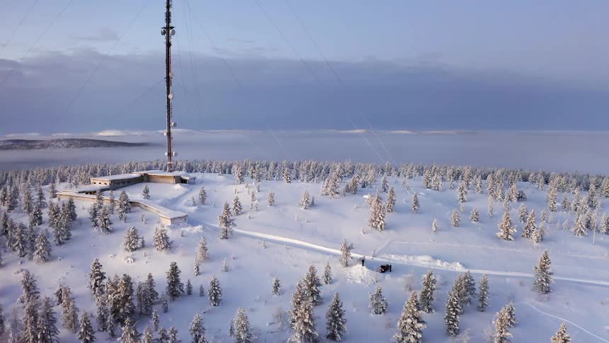Landscape of snow covered land with a building trees and two people by a car