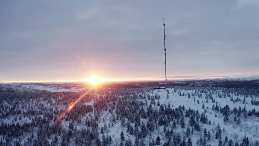 The sun sets over a vast snow covered forest