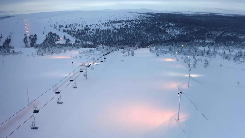 A ski lift runs above a snow covered slope