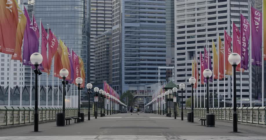 A wide walking bridge lined with colorful banners in a metropolis during the day
