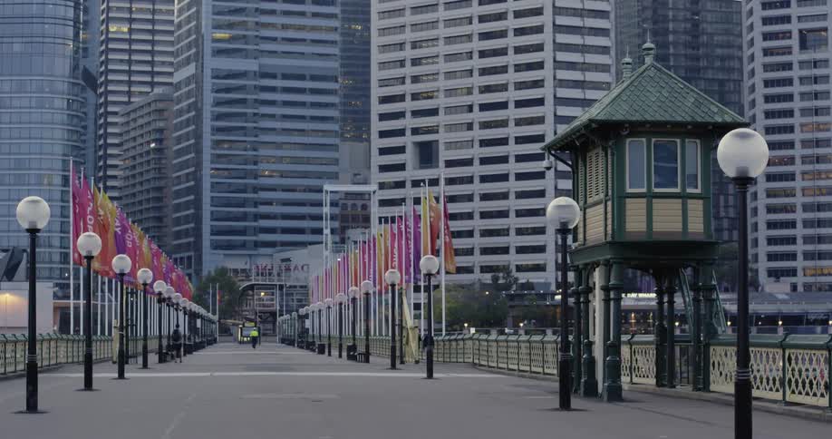 Colorful flags and lamp posts line a sidewalk that heads into downtown