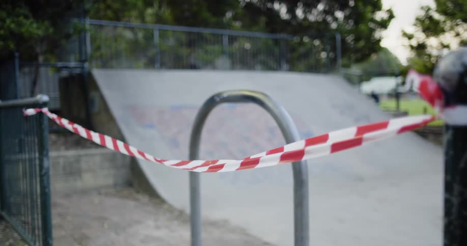 A checked rope is tied between two posts blocking a public park half pipe