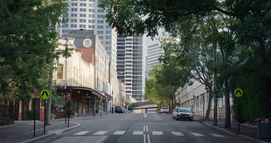 Cars sit parked at the side of the road across from retail stores in the city