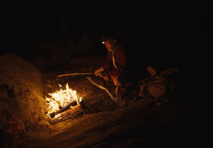 A man stokes his camp fire