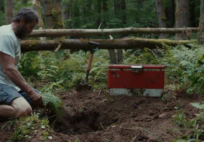 A man pulls a large tool box out of a hole in the ground