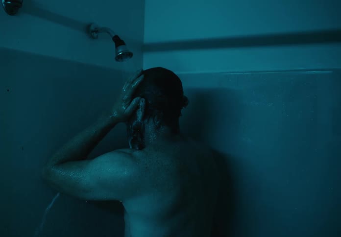 Man rinsing shampoo from head under the shower