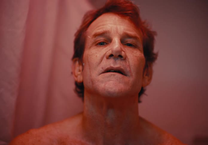 Man wiping his face with a white wash rag in the bathroom