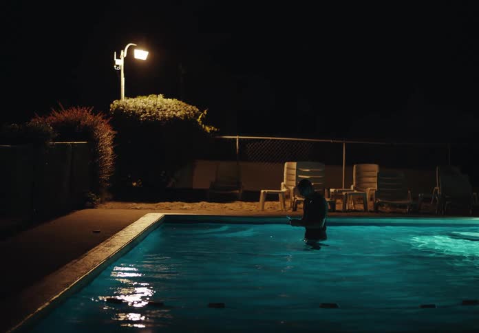A man walks back and forth in the pool with a tablet