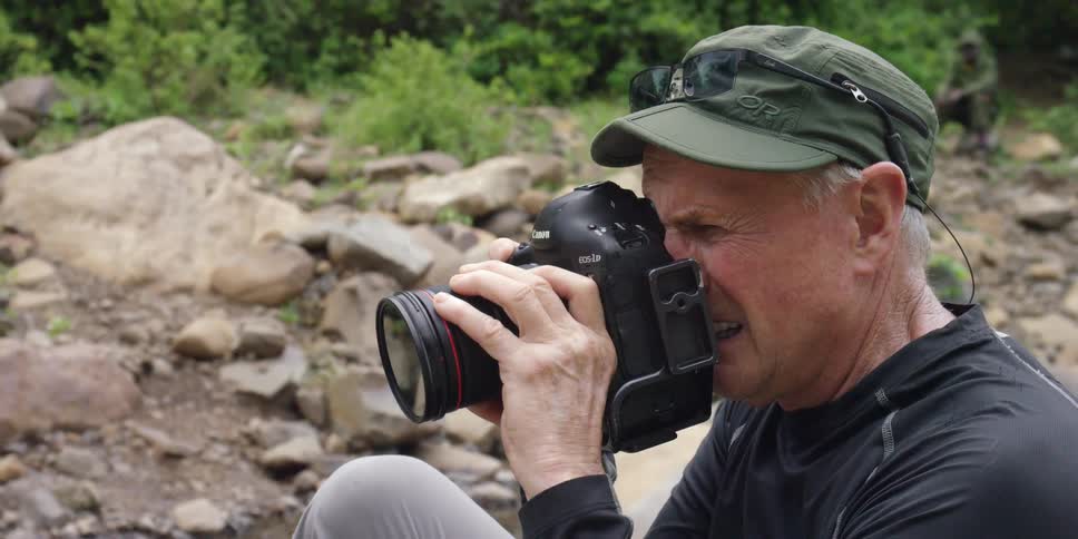 A man is taking photographs while sitting on rocks