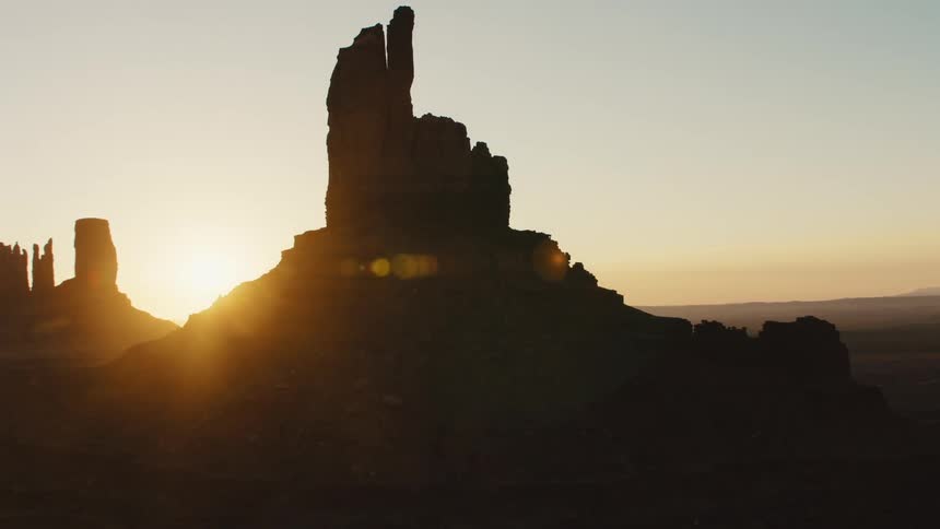 A mesa in the badlands shrouded in shadow due to the low sun