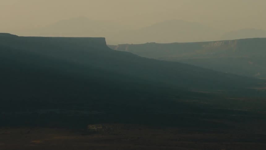 Mountains and mesas sit under a cloudy sky