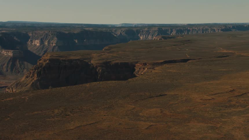 A canyon in the desert with the sky and clouds in the background