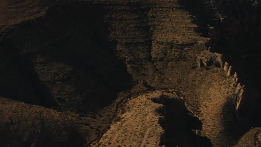 Aerial view of the geological formations in a canyon throught the badlands desert at sunset