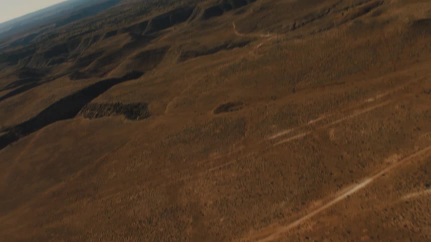 Desert with large crevices sits under a blue sky
