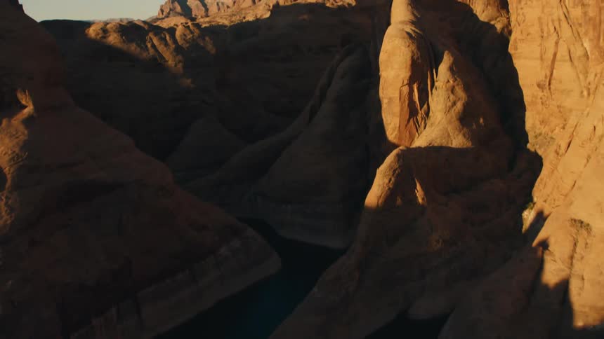 River winds through canyon remaining in shadow under clear blue sky