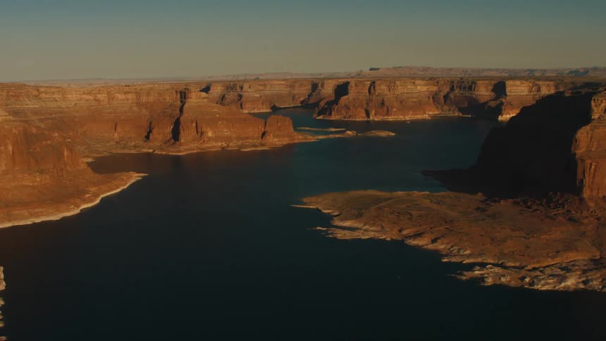 A deep blue river winds through the valley of a canyon