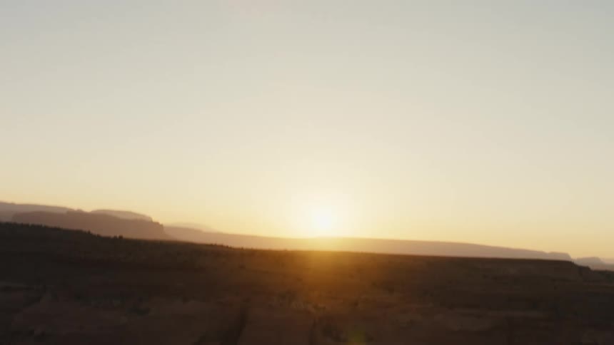 Aerial view of the sun setting over cliffs and canyons