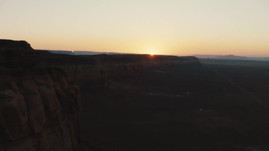 A desert with plateaus with the sky clouds and the sunset in the background