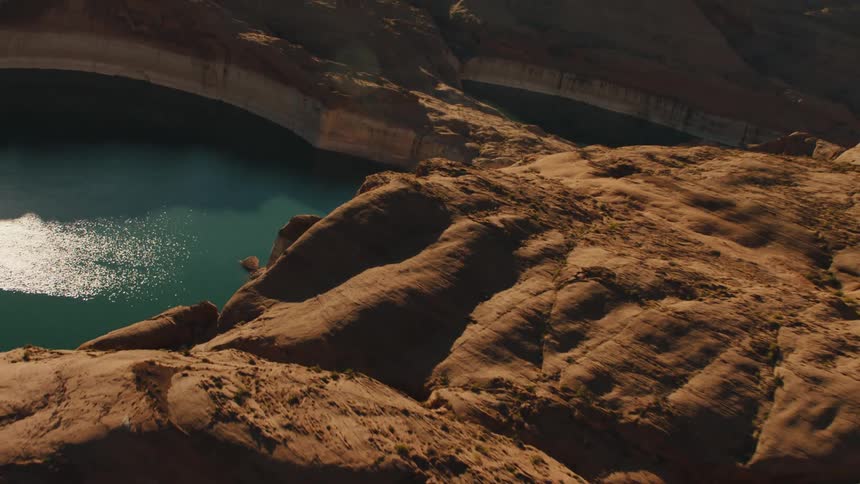 A tranquil lake near rocky cliffs is illuminated by the sun