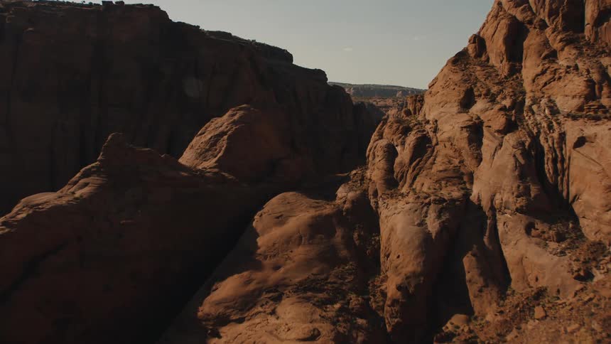 A canyon with a cliff with the sky and clouds in the background