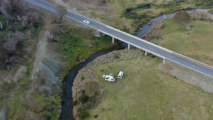 Two vans are parked near a stream