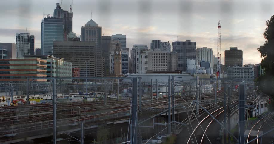 Train tracks with a train moving with buildings and skyscrapers in the background