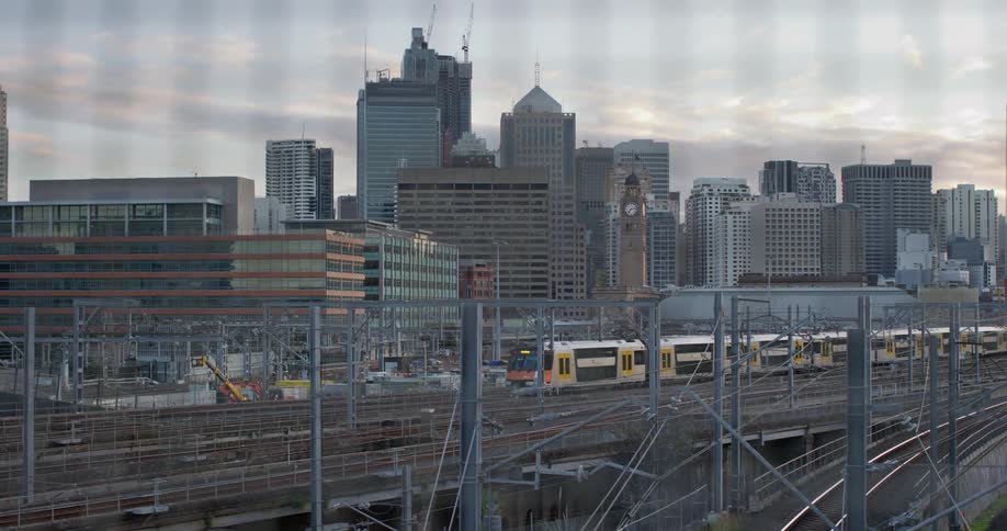 The train arrives at platform in the city with tall buildings in the background
