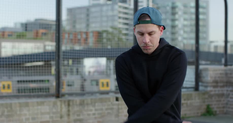 A man with a hat jumping rope with a train and buildings in the background
