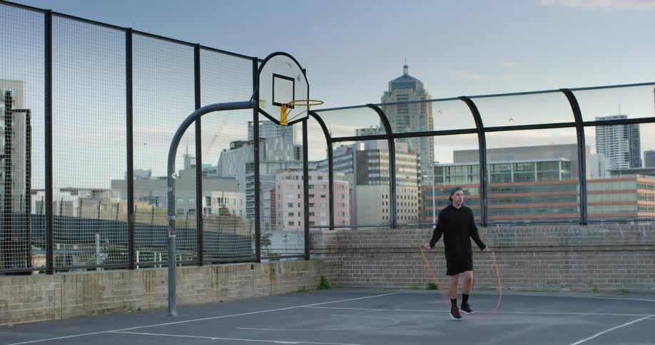 A man jumping rope on a rooftop basketball court