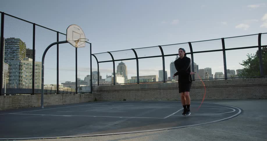 A man skipping rope on a rooftop basketball court