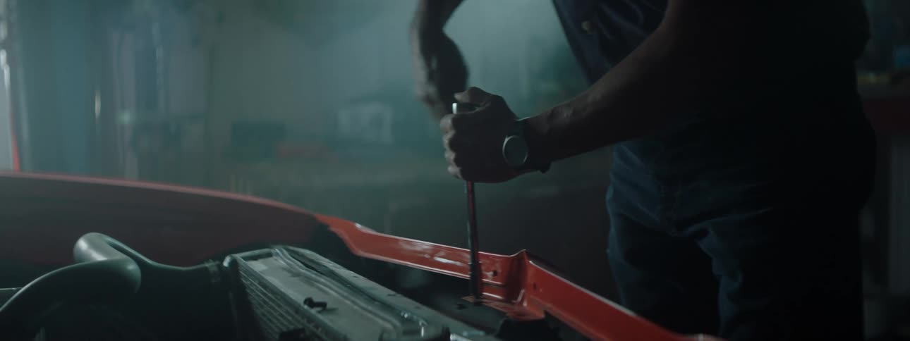 A man works on his car in the dark garage
