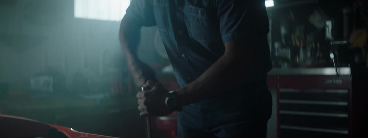 Man turns socket wrench in garage with window and tool chest in background