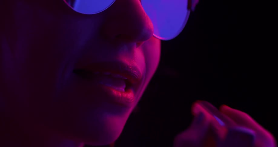 Close up of a woman wearing sunglasses using lipstick on her lips
