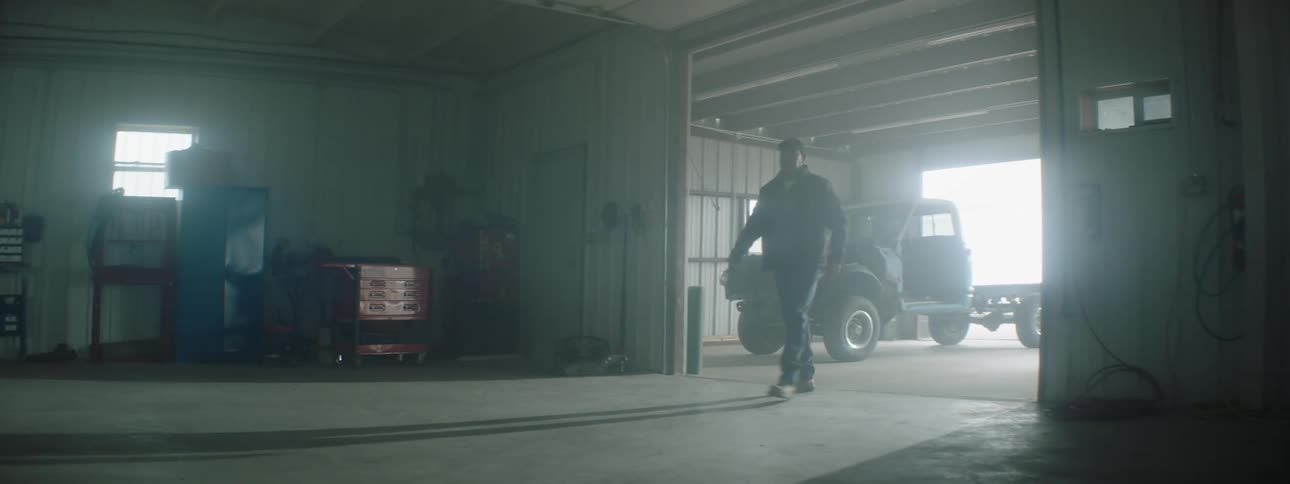 Man opens up the garage door of a car repair workshop