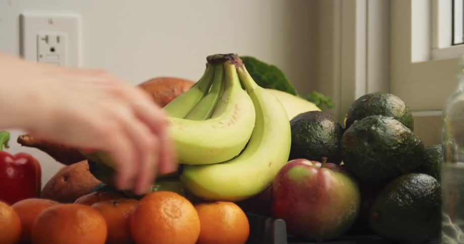 Woman placing fresh produce onto a large pile on the counter
