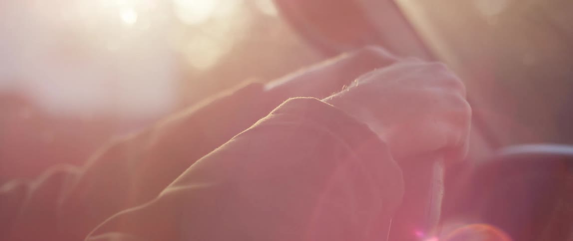 Close up of a mans hands on the steering wheel of a moving car at sunset